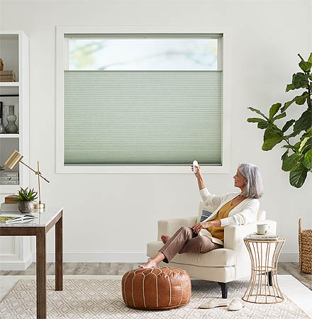Woman operating motorized shade by remote control